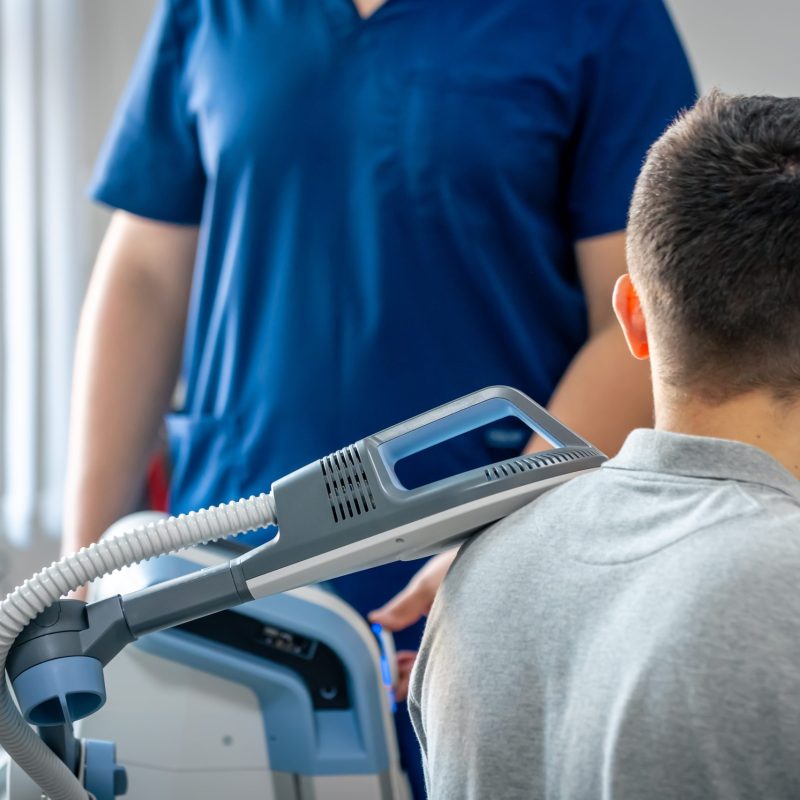 Electromagnetic therapy of the back, physiotherapist doctor uses medical equipment for highly effective pain treatment and inflammation back, the magnetic field, rehabilitation, magnetotherapy.